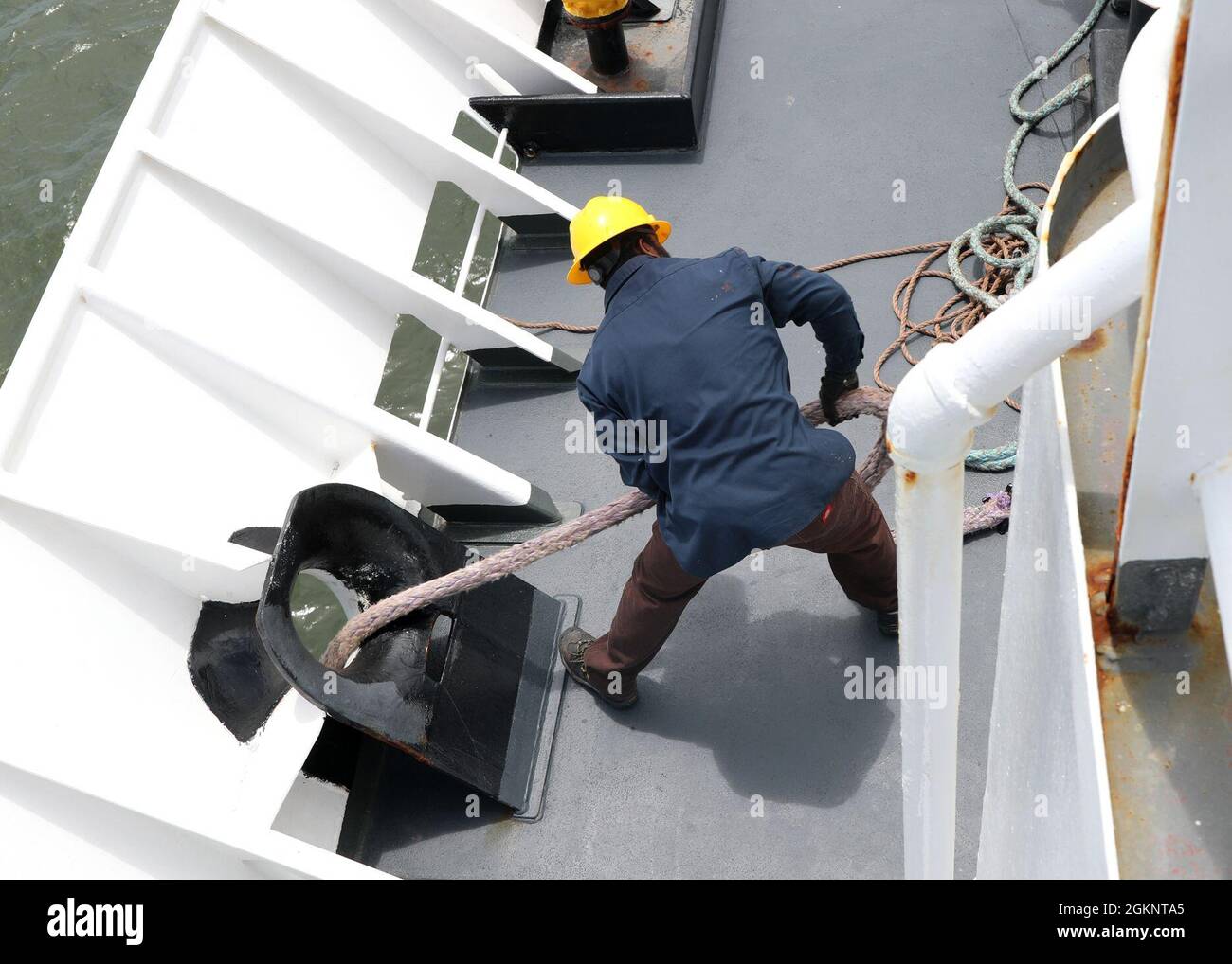 210608-N-OH262-0751 NORFOLK, Va. (June 8, 2021)--A civilian mariner assigned to Military Sealift Command's oceanographic survey ship USNS Bruce C. Heezen (T-AGS 64) pulls a mooring line aboard the vessel as the ship pulls into Naval Station Norfolk, June 8. The mariners who crew USNS Bruce C. Heezen are employed by the contracted operating company Ocean Ships, Inc. Stock Photo