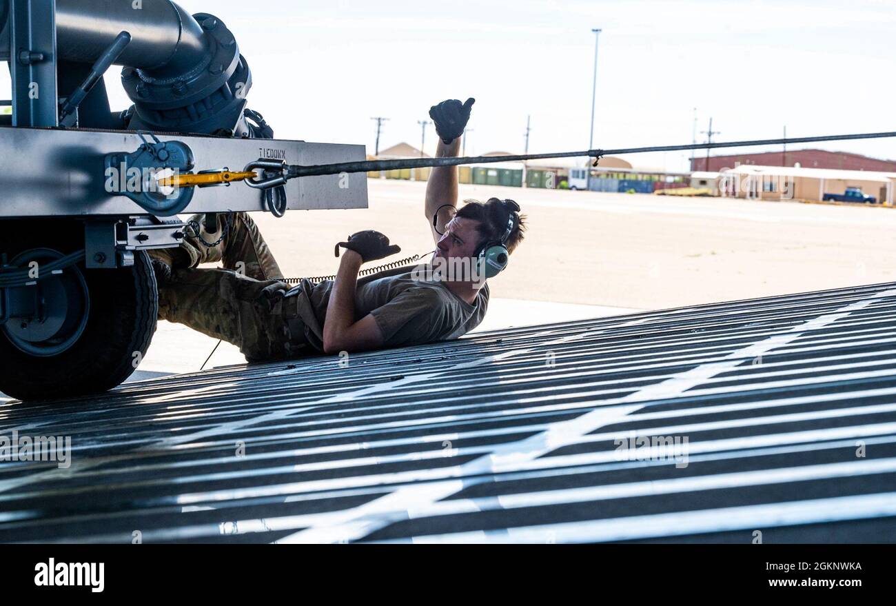 Staff Sgt. John Dittess, 9th Airlift Squadron loadmaster, assists in marshaling aircraft ground equipment onto a Dover Air Force Base C-5M Super Galaxy during a Major Command Service Tail Trainer, at Holloman AFB, June 8, 2021. Loadmasters from the 9th AS coordinated cargo with Airmen from Air Education and Training Command’s 49th Wing and Air Force Materiel Command’s 635th Material Maintenance Group to complete the 10-day MSTT. Over the course of the training, Airmen loaded and unloaded 320,085 pounds of cargo, including palletized cargo, AGE, a fuel truck and a K-loader. Stock Photo