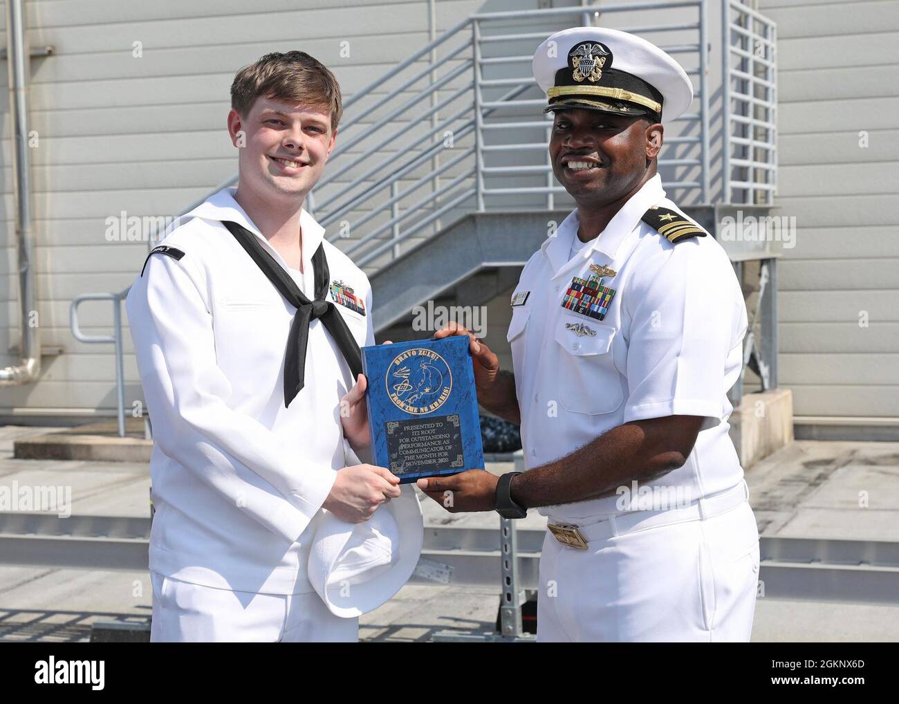 Lt. Cmdr. Rod Smith, Commander, Submarine Group Seven N6 Department Head, presents Conneaut, Ohio native, Information Systems Technician 2nd Class Nicholas Root with a Communicator of the Month recognition plaque during an awards ceremony held at headquarters June 8 2021. Stock Photo
