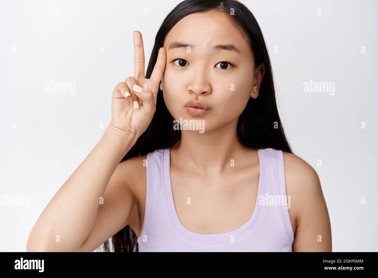 Cute asian woman showing kawaii peace sign near clean face without makeup,  standing over white background Stock Photo - Alamy