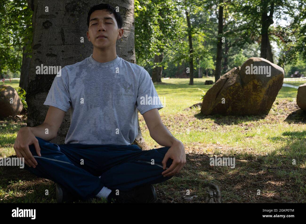 U.S. Air Force Airman Edgar Grimaldo, 86th Airlift Wing Public Affairs apprentice rests under a tree at Ramstein Air Base, Germany, June 9, 2021. According to the 86 AW safety office, as temperatures increase frequent breaks are recommended when playing outdoors to keep a healthy lifestyle. Stock Photo