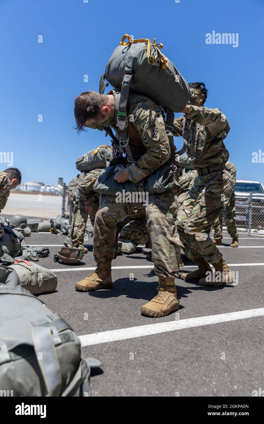 U.S. Army Soldiers with 301st Tactical Psychological Operations, PSYOP, Company (Airborne),14th PSYOP Battalion, 7th PSYOP Group, assist each other with their static-line chutes before performing pre-jump checks during a U.S. Air Force KC-130 Hercules static-line jump exercise at Naval Base Coronado, California, June 11, 2021. The 301st TCP invited I Marine Expeditionary Force Information Group PSYOP Marines to observe jump training before attending the U.S. Army Airborne school. Gaining jump qualifications enables I MIG to effectively integrate and support I Marine Expeditionary Force informa Stock Photo
