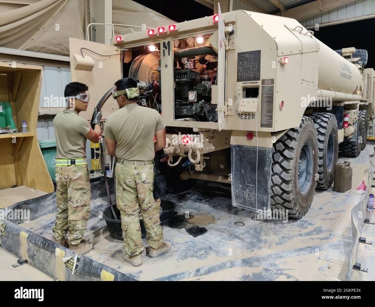 Spc. Rogelio Chavez and Spc. Marvin Caparas, from E Company, 1st Battalion, 168th Aviation Regiment (General Support Aviation Battalion), recirculate the fuel in a Heavy Expanded Mobility Tactical Truck (HEMTT) on the night shift at the motor pool at Camp Buehring, Kuwait. The fuel is recirculated to remove condensation and contaminants before fueling aircraft. Stock Photo