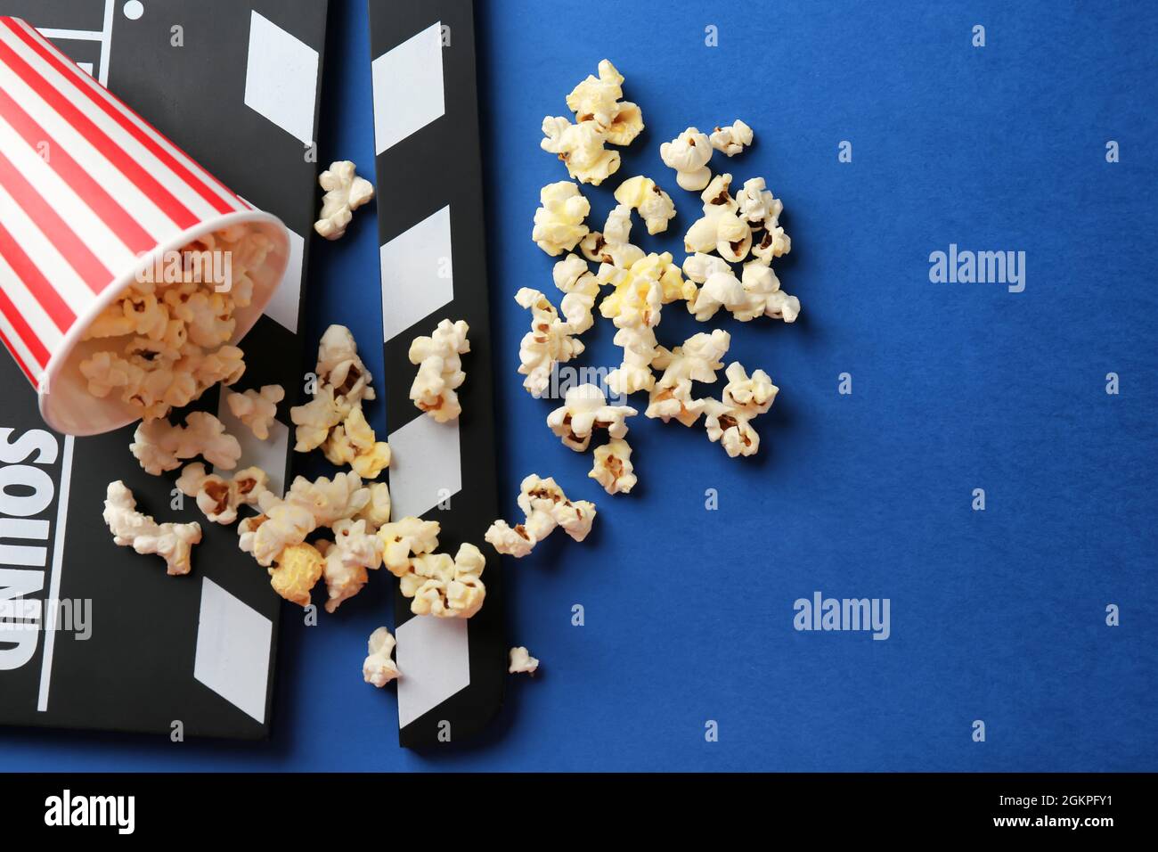 Paper cup with popcorn and movie clapper on color background Stock ...