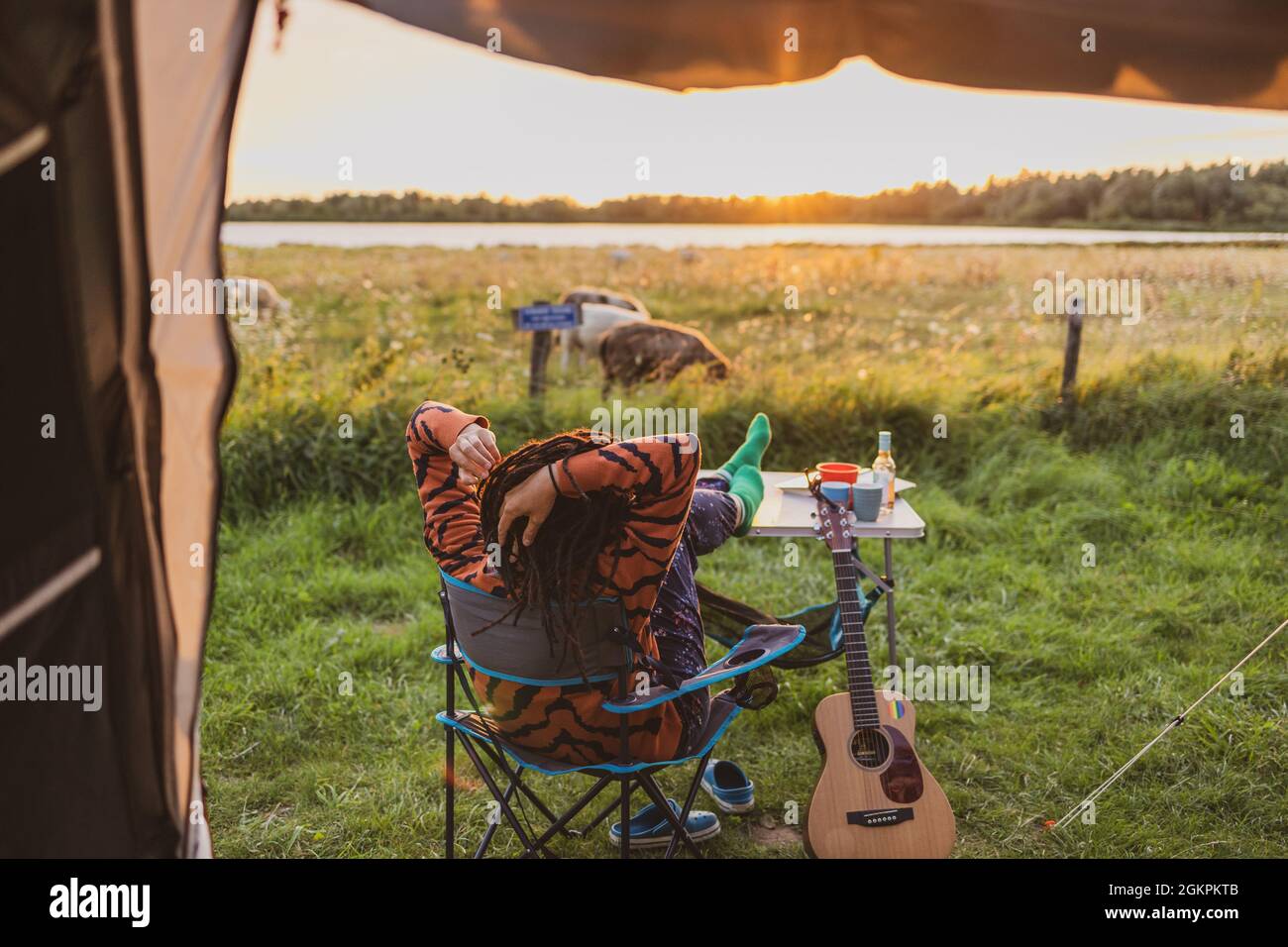Woman relaxing in front of the tent during sunset Stock Photo