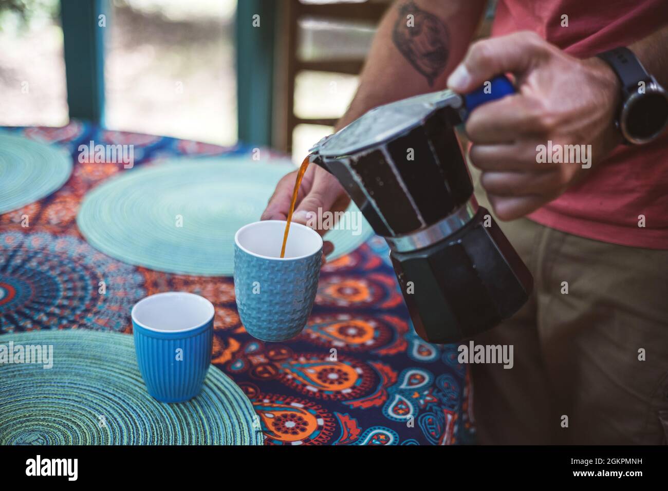 Man pouring coffee from a coffee maker into a cup Stock Photo