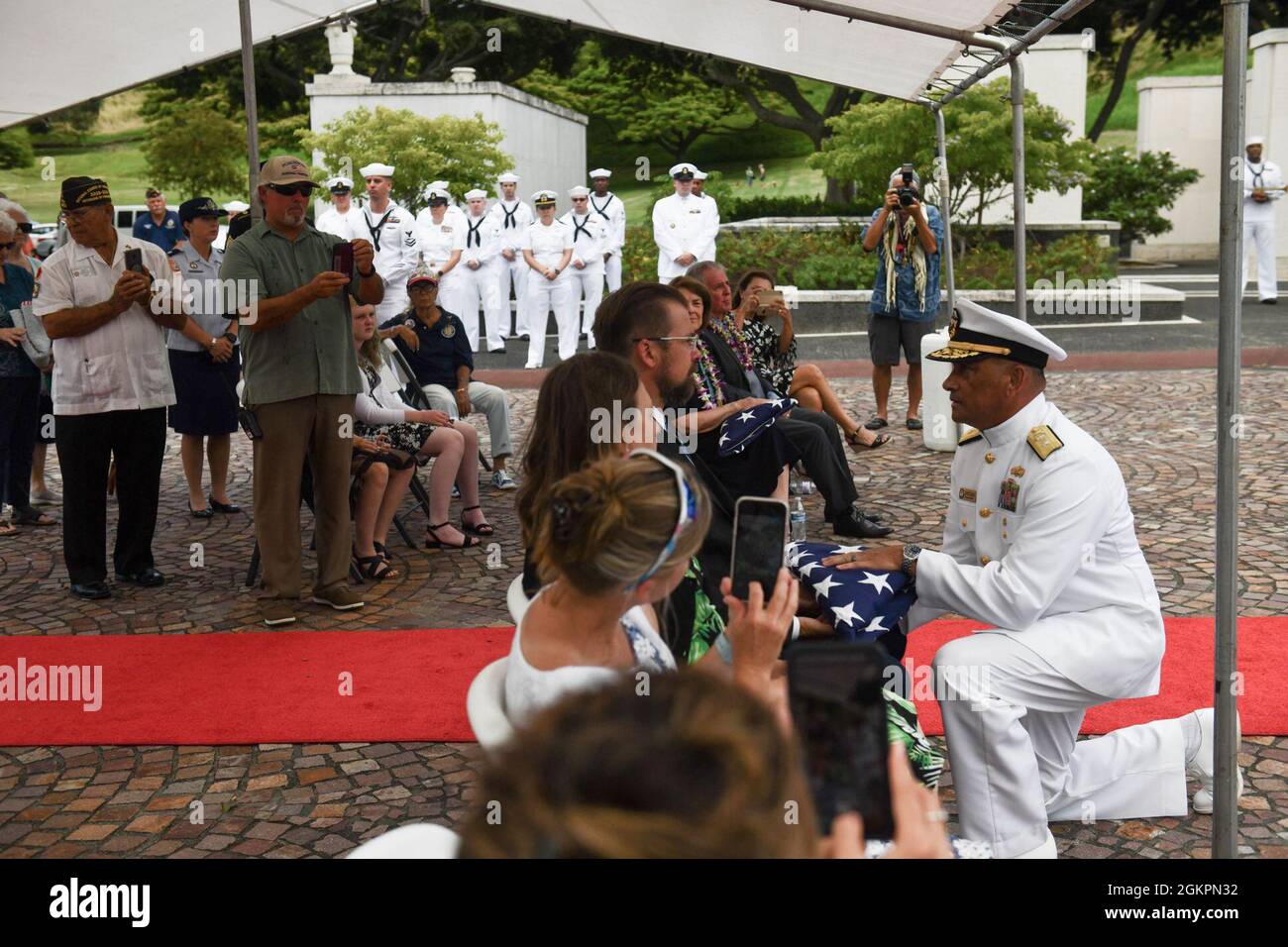 U.S. Navy Rear Adm. Darius Banaji, deputy director for operations for the Defense POW/MIA Accounting Agency (DPAA), presents an American flag to a member of the Trapp brother’s family during a funeral for the Trapp brothers at the National Memorial Cemetery of the Pacific, Honolulu, Hawaii, June 15, 2021. The Trapp brothers were assigned to the USS Oklahoma, which sustained fire from Japanese aircraft and multiple torpedo hits causing the ship to capsize and resulted in the deaths of more than 400 crew members on Dec. 7, 1941, at Ford Island, Pearl Harbor. The Trapp brothers were recently iden Stock Photo