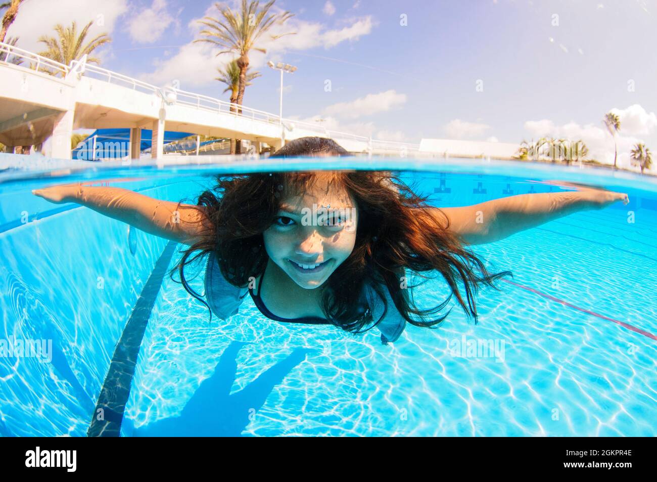 A dressed 12 year old female teen free diving under water in a swimming pool. Model release available Stock Photo