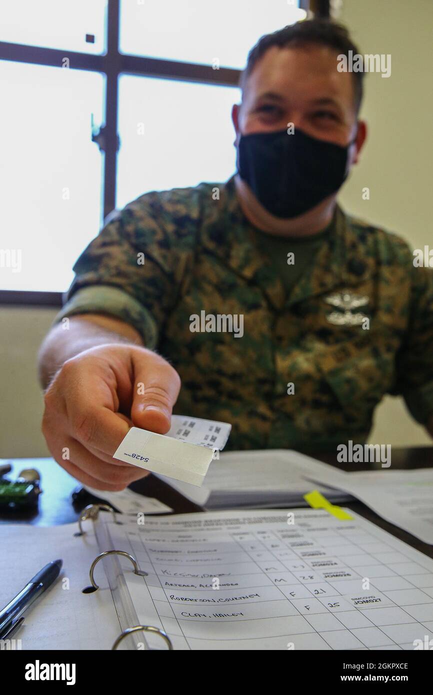 U.S. Navy Petty Officer Third Class Tyler Brown, hospital corpsman with 3d Marine Logistics Group, hands out medical stickers to identify blood and saliva samples during a research study conducted by U.S. Naval Medical Research Unit on Camp Kinser, Okinawa, Japan, June 15, 2021. The study was conducted amongst active duty Navy and Marine Corps personnel to investigate the percentage of Marines and Sailors previously infected with SARS-CoV-2, the virus that causes COVID-19. The purpose of the study is to understand how widespread COVID-19 infections are throughout the United States Indo-Pacific Stock Photo