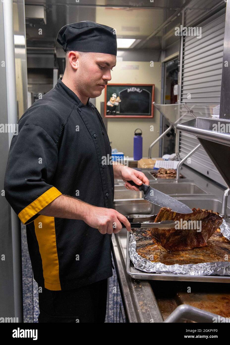 210616-N-WU807-1019 ANDAMAN SEA (June 16, 2021) Culinary Specialist 3rd Class Matthew Deluca, from Cincinnati, prepares ribs for dinner aboard Independence-variant littoral combat ship USS Charleston (LCS 18), June 16. Charleston, part of Destroyer Squadron Seven, is on a rotational deployment operating in the U.S. 7th fleet area of operations to enhance interoperability with partners and serve as a ready-response force in support of a free and open Indo-Pacific region. Stock Photo