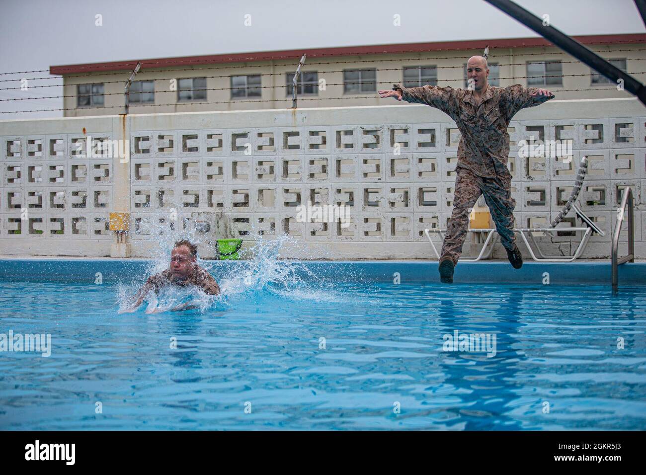 U.S. Navy Petty Officer 2nd Class Christopher Walters, left, a hospital corpsman with 3d Medical Battalion, 3d Marine Logistics Group, and Marine Corps Staff Sgt. Joseph Colvin, the storage staff noncommissioned officer in charge with Ammunition Company, 3d Supply Battalion, Combat Logistics Regiment 35, 3d Marine Logistics Group, III Marine Expeditionary Force, conduct training during the water survival advanced (WSA) course on Marine Corps Air Station Futenma, Okinawa, Japan, June 17, 2021. WSA is the highest swim qualification Marines and sailors can obtain before moving onto the next echel Stock Photo