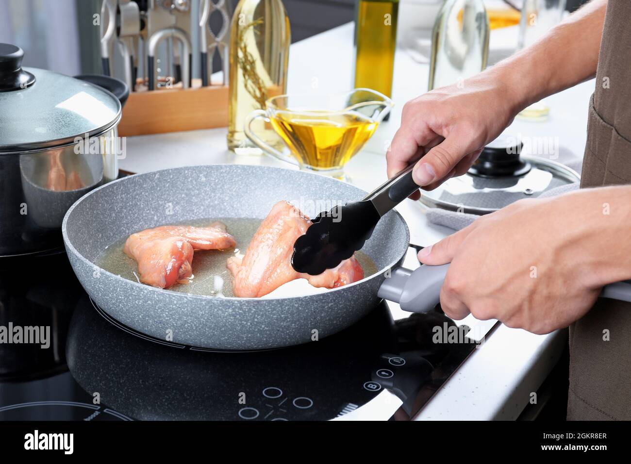 Man cooking chicken wings in frying pan Stock Photo Alamy
