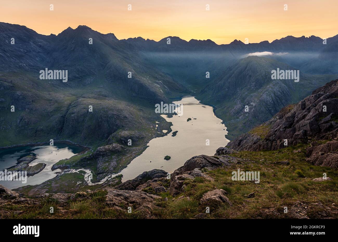 The sun setting behind the Black Cuillin Ridge with the remote Loch Coruisk in the glen below, Isle of Skye, Inner Hebrides, Scotland, United Kingdom Stock Photo