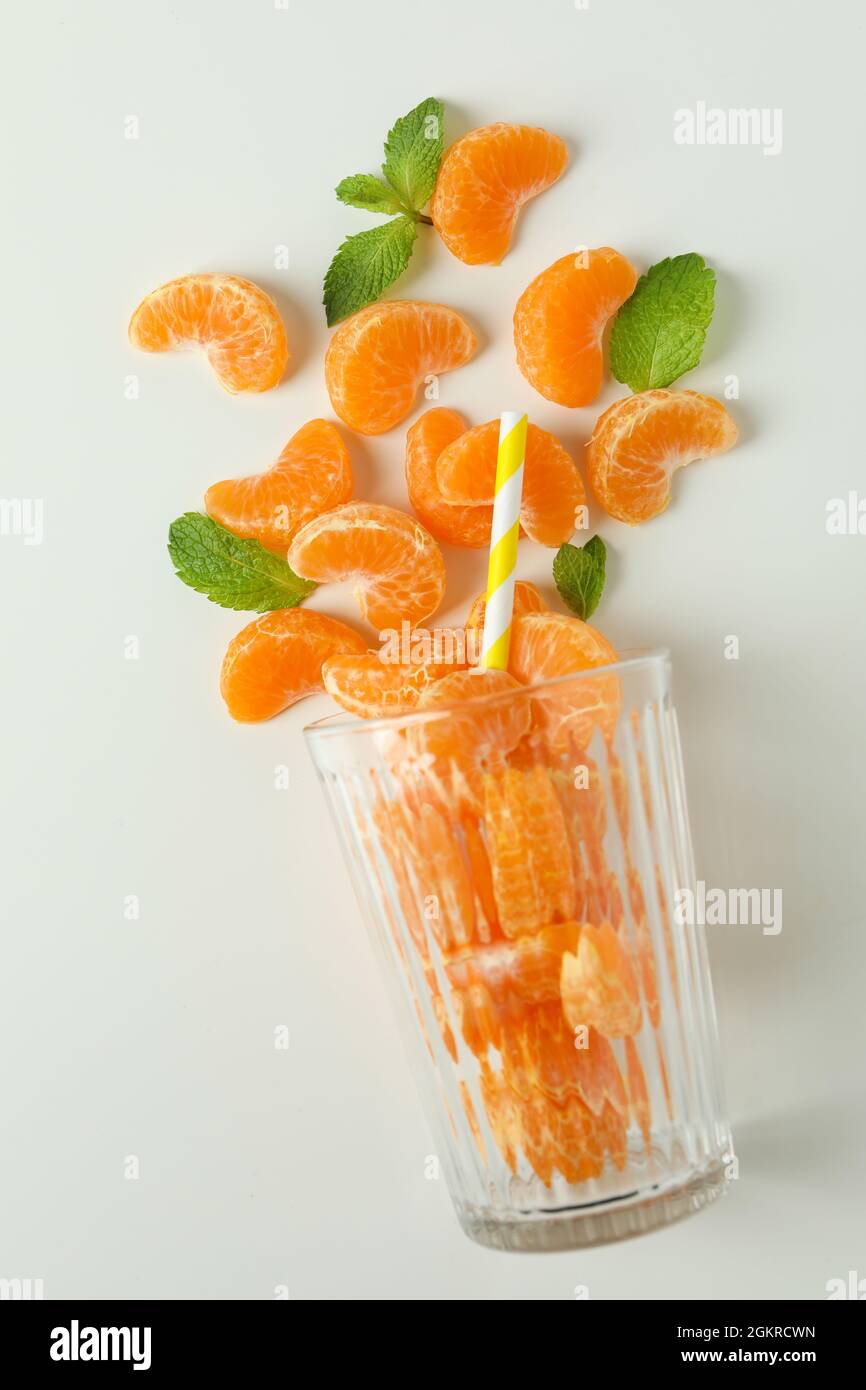 Concept of making mandarin juice with glass with mandarins on white