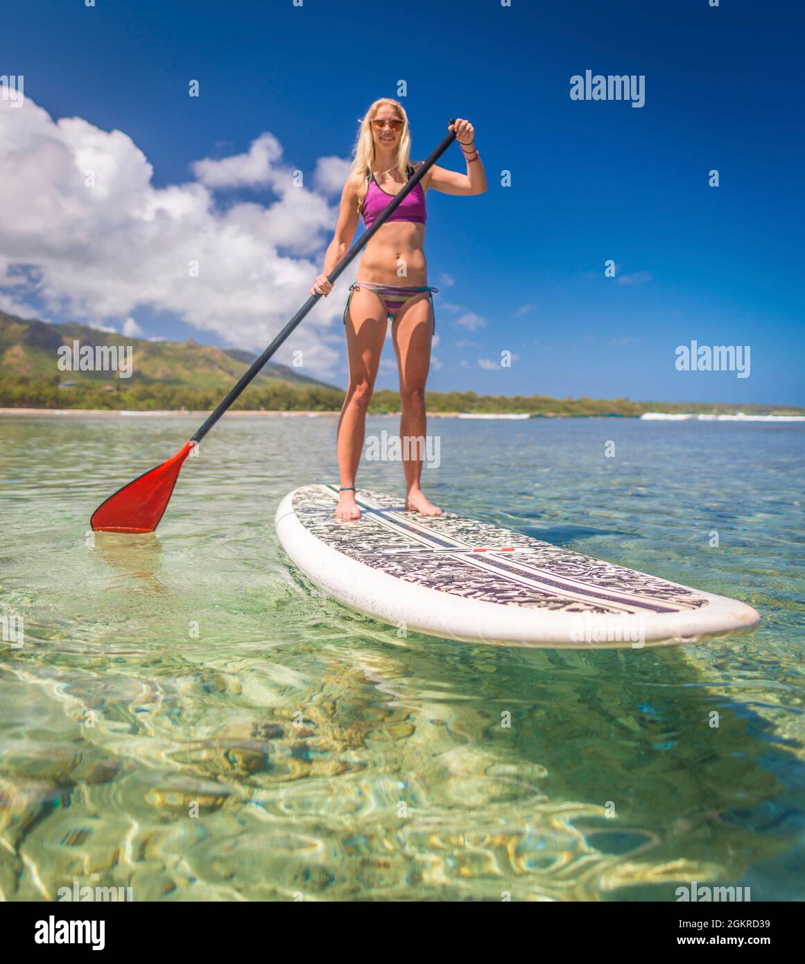 A young athletic woman using a stand-up paddle-board in a calm bay of Hawaii, United States of America, Pacific Stock Photo