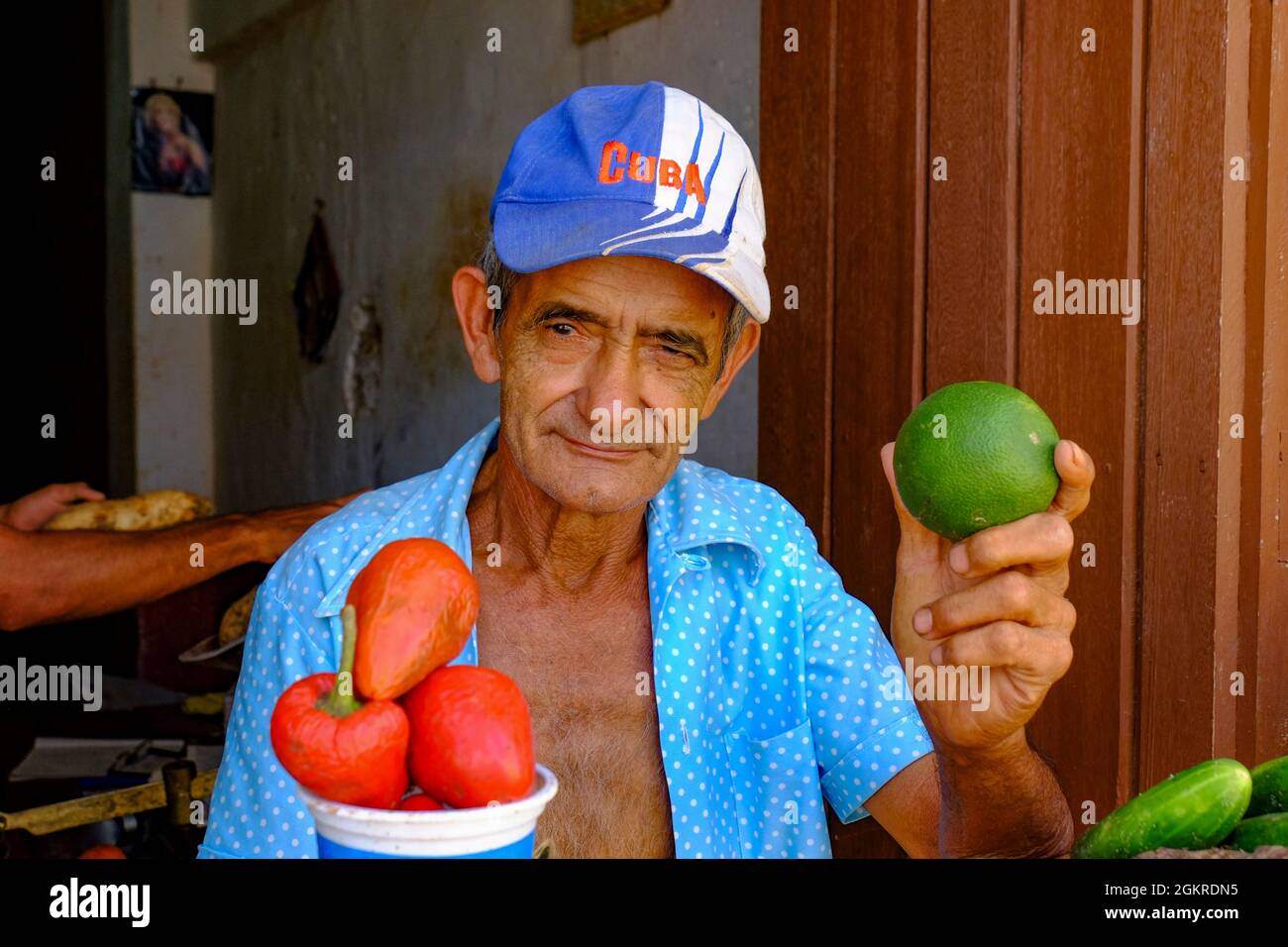 A man at a vegetable stand holds up a lime, Trinidad, Cuba, West Indies, Central America Stock Photo