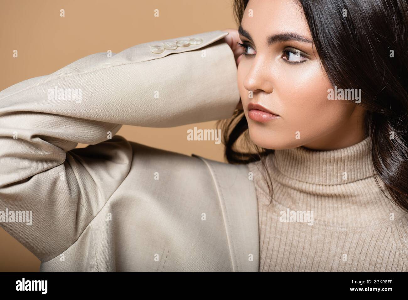 pretty model in turtleneck and blazer looking away isolated on beige Stock Photo