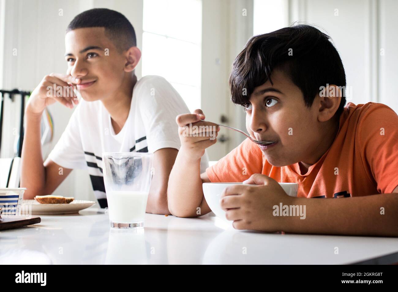 Two boys brothers eating breakfast at the kitchen table in the morning