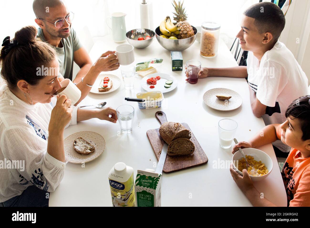 A family, mother and father, and two boys, brothers, eating breakfast