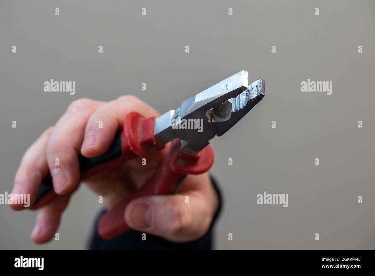 A portrait of the hand of a person holding universal orcombination pliers like they are about to hold or squeeze something with the work tool and to d Stock Photo