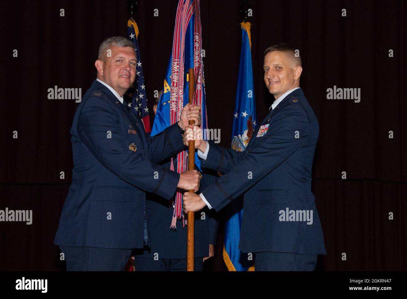 Maxwell AFB, Ala. - Col. Anthony Babcock (left), Commander, Thomas N. Barnes Center for Enlisted Education, passes the guidon to Lieut. Col. Kevin R. Pond during the Community College of the Air Force (CCAF) change of command ceremony held at the SNCO Academy Auditorium on Jun. 22, 2021. Stock Photo