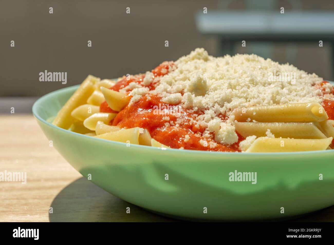 Popular recipe for children of macaroni with tomato and grated cheese on a blue plate Stock Photo