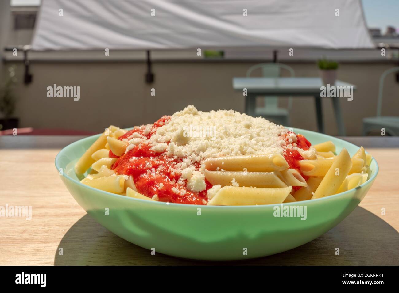 Blue plate of macaroni and cheese and tomato served on an urban terrace Stock Photo