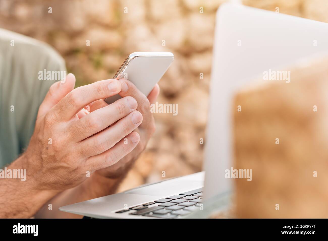 Freelancer and digital nomad working on smartphone and laptop computer during summer vacation holiday on apartment terrace in morning Stock Photo