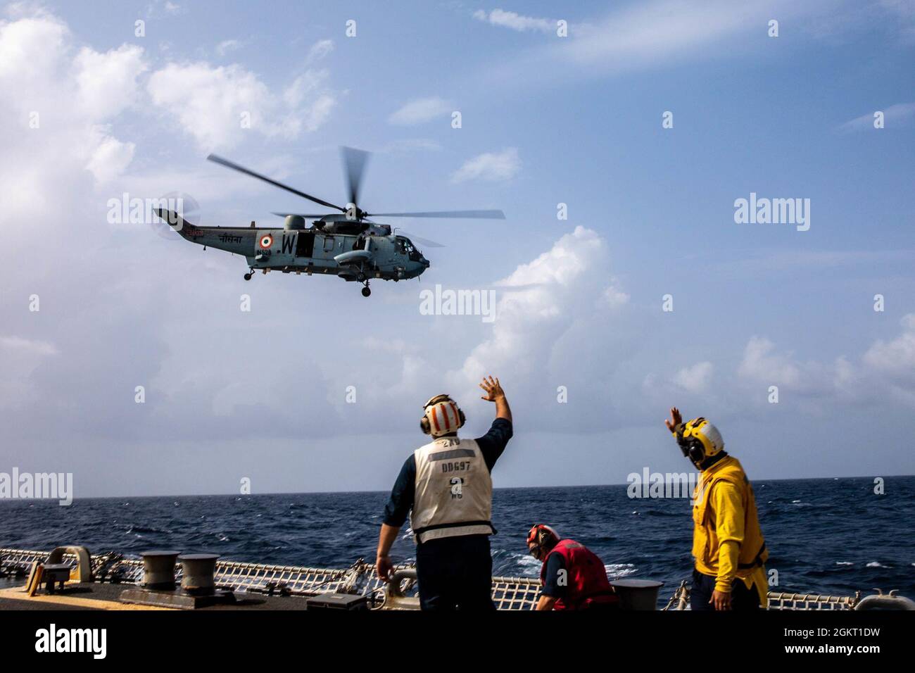 INDIAN OCEAN (June 24, 2021) – An SH-3 Sea King, assigned to the Indian Naval Air Arm, flies past the Arleigh Burke-class guided-missile destroyer USS Halsey (DDG 97) during a bilateral exercise. Halsey is attached to Commander, Task Force 70/Carrier Strike Group 5 conducting underway operations in support of a free and open Indo-Pacific. Stock Photo