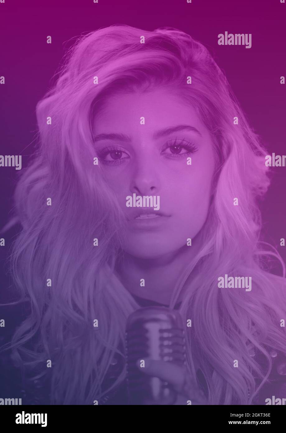 Portrait of caucasian female singer holding a microphone against purple background Stock Photo