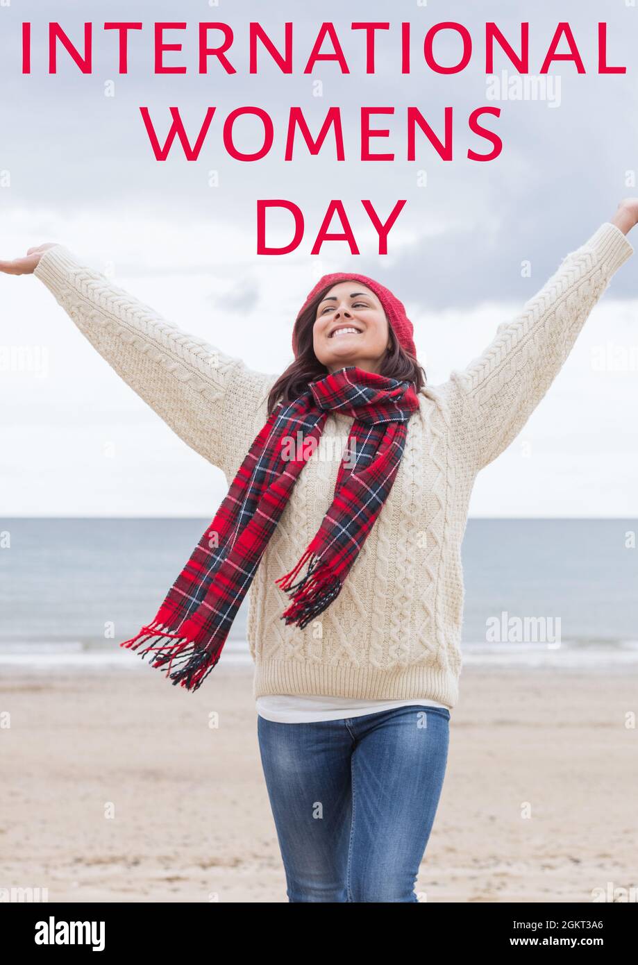 International women's day text over woman standing with arms wide open at the beach Stock Photo