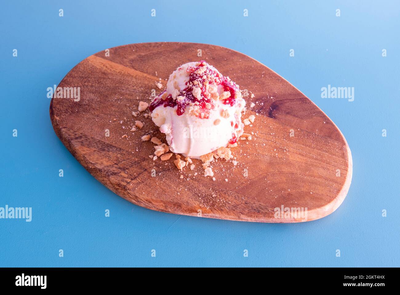 ball of cheesecake ice cream with red berry jam and cookie pieces Stock Photo