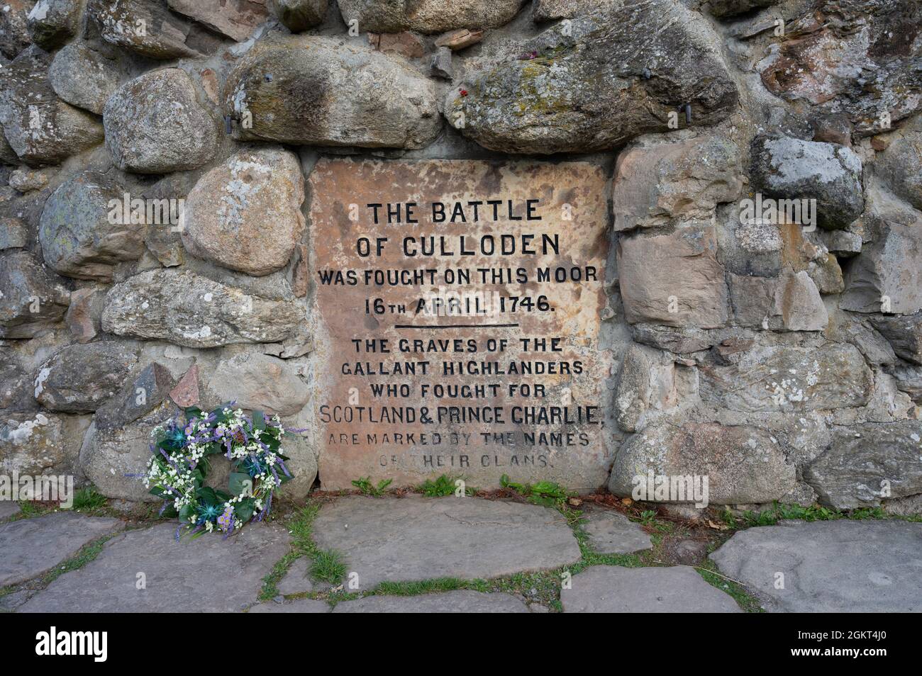 Close up of inscription on Culloden monument, remembering the battle here between the Scottish Jacobites and the English. Flower wreath to side. Stock Photo