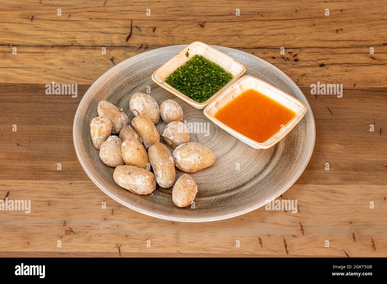 Canarian recipe of wrinkled potatoes with sauces on porcelain plate and wooden table Stock Photo