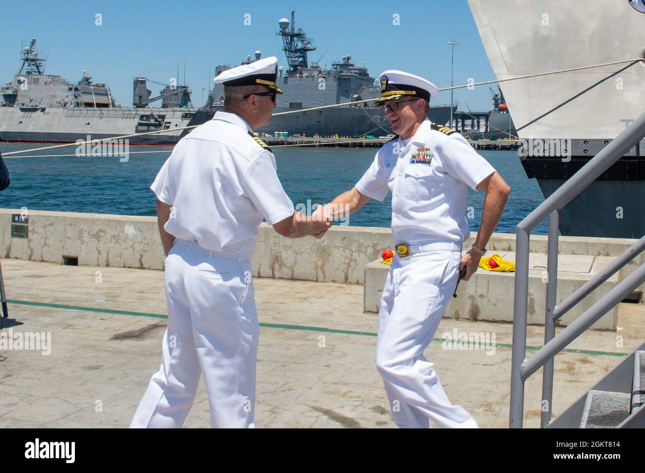 210626-N-ZS023-1021 NAVAL BASE SAN DIEGO (June 26, 2021) – Cmdr.  Christopher Wolff, right, commanding officer of the Independence-variant  littoral combat ship USS Mobile (LCS 26) blue crew, greets Capt. Jack Fay,  left,