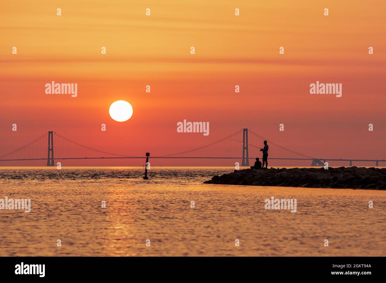 Silhouette of two men fishing with the Great Belt Bridge in the background, Denmark Stock Photo
