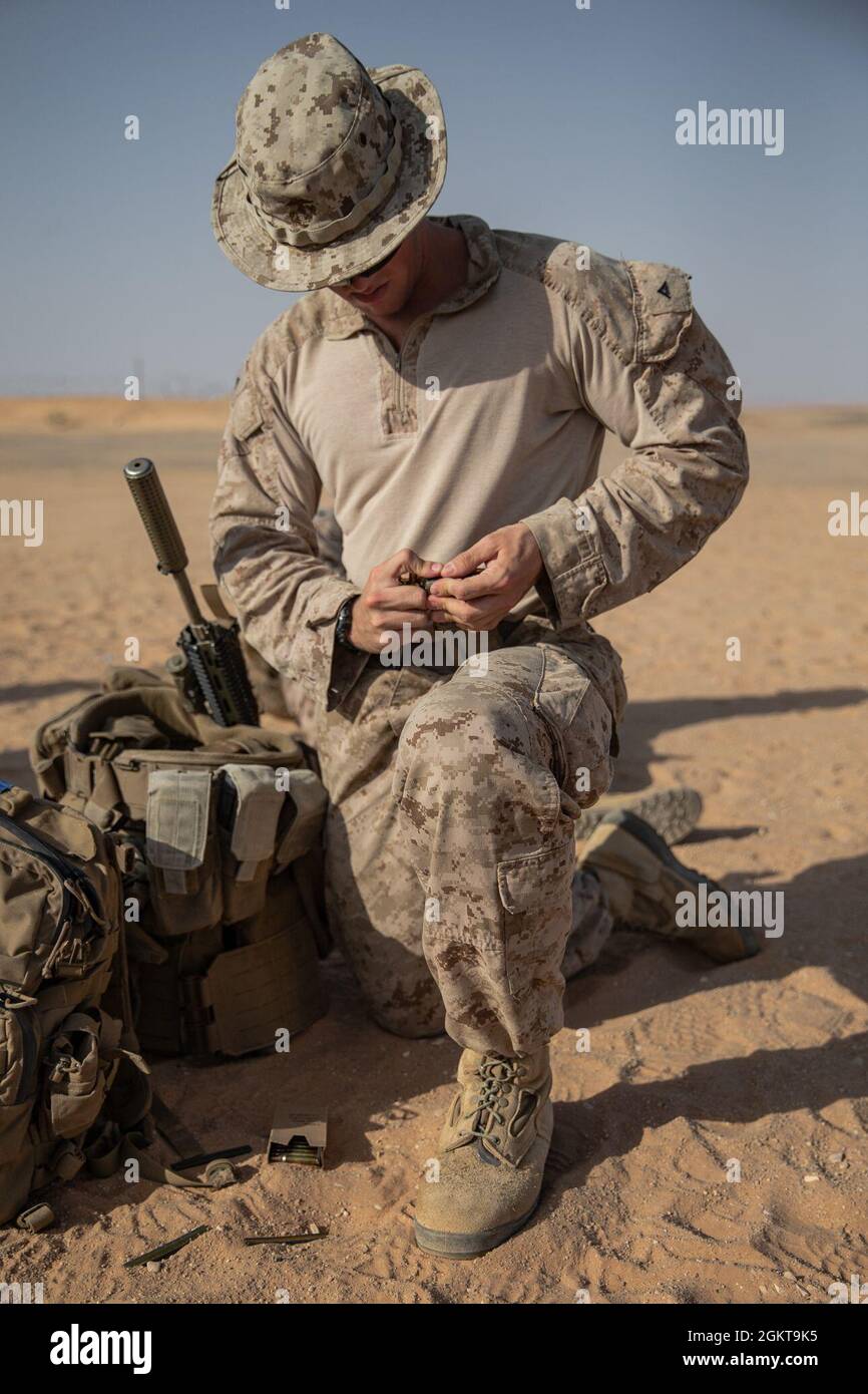 A U.S. Marine with 2nd Battalion, 1st Marine Regiment, assigned to Special Purpose Marine Air-Ground Task Force – Crisis Response – Central Command (SPMAGTF-CR-CC), loads a magazine before a Combat Marksmanship Program (CMP) range in the Kingdom of Saudi Arabia, June 26, 2021. The CMP range allows Marines to maintain rifle and machine gun proficiency while being put through various courses of fire. The SPMAGTF-CR-CC is a crisis response force, prepared to deploy a variety of capabilities across the region. Stock Photo