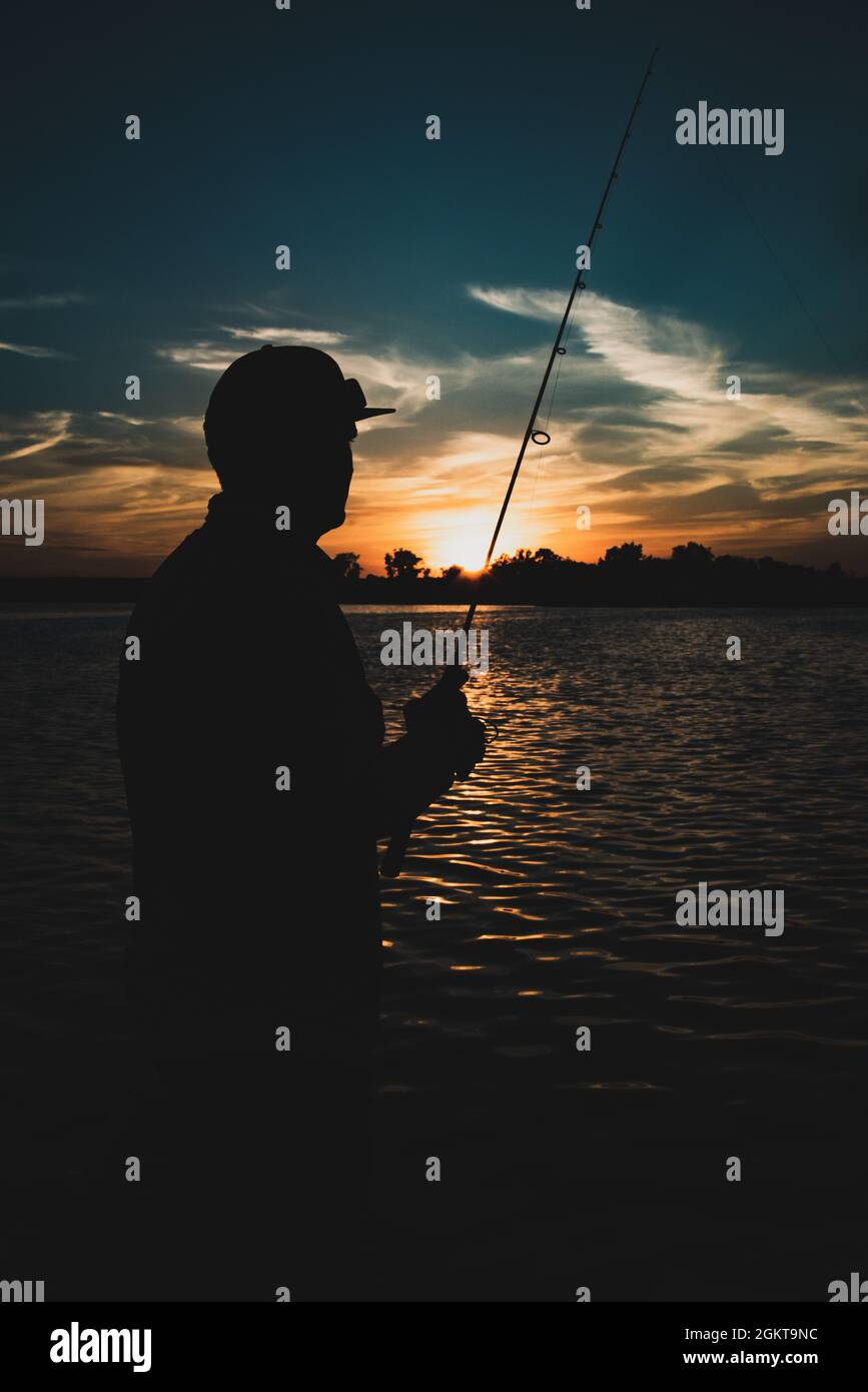 fisherman silhouette in sunset Stock Photo - Alamy