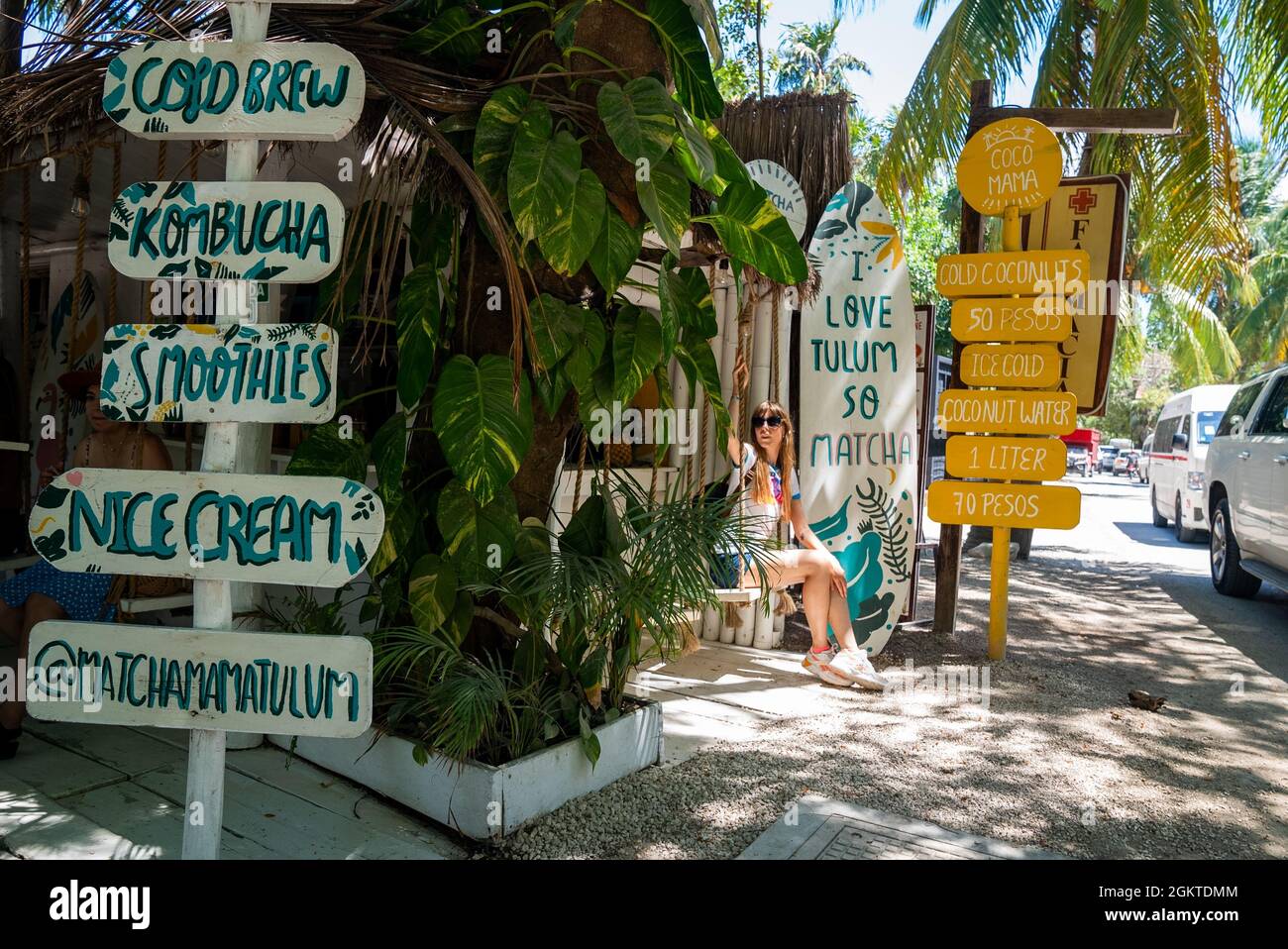 Woman sitting on swing seat of coconut shop with drink menu at roadside
