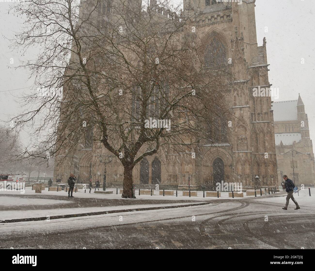 A person walks past York Minster as snow is falling, York, UK Stock Photo