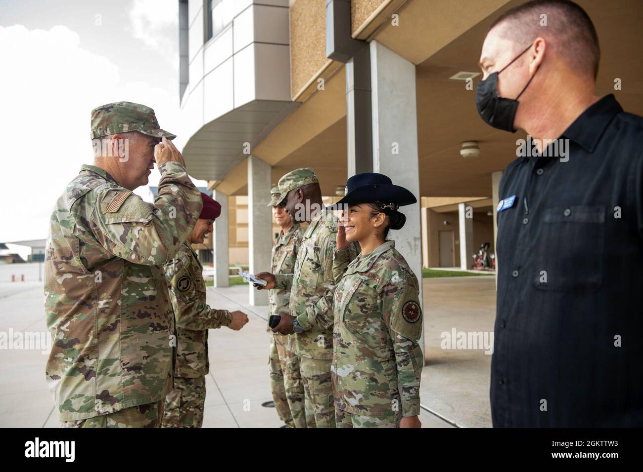U.S. Air Force Gen. John E. Hyten (left), vice chairman of the Joint Chiefs of Staff, returns a salute after presenting Tech. Sgt. Genesis Infante (center), 737th Training Group military training instructor, a coin during the USO Summer Tour, July 1, 2021, at Joint Base San Antonio-Lackland, Texas. The USO brings shows to hundreds of thousands of American service members around the world. This is the first in-person event since the beginning of the COVID-19 pandemic impacted U.S. service members worldwide. Stock Photo