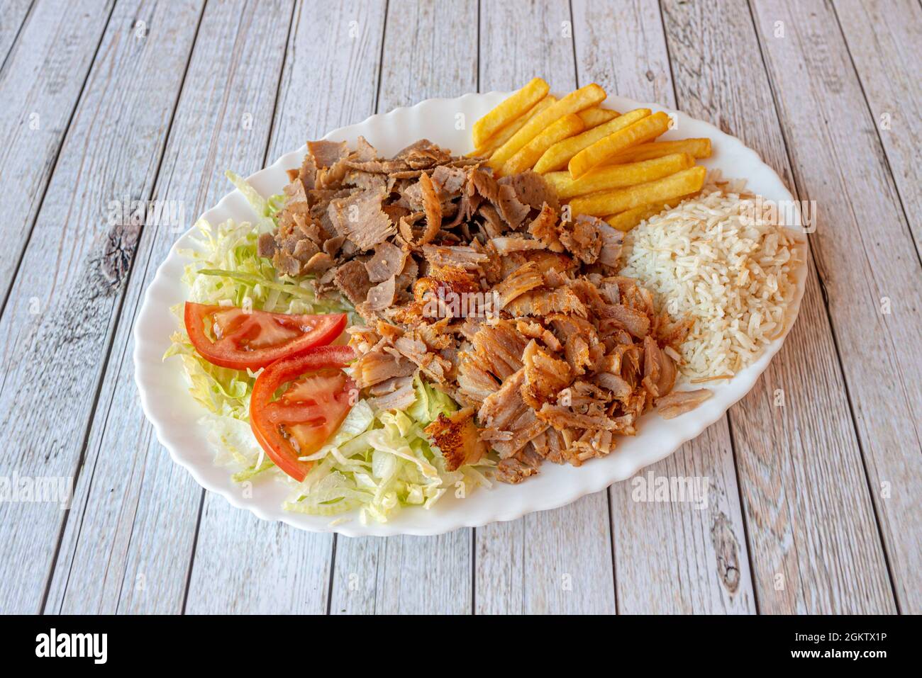 Kebab tray with mixed roast chicken and lamb meat garnished with white rice,  French fries and lettuce and tomato salad Stock Photo - Alamy