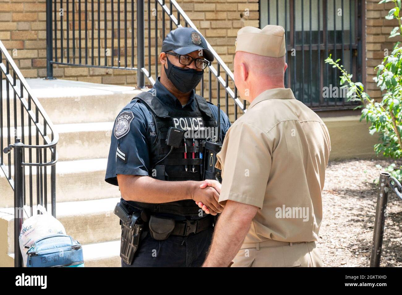 WASHINGTON, DC (July 1, 2021) – Capt. Mark Burns (right), Naval Support Activity Washington commanding officer, greets a civilian police officer onboard Washington Navy Yard. Stock Photo