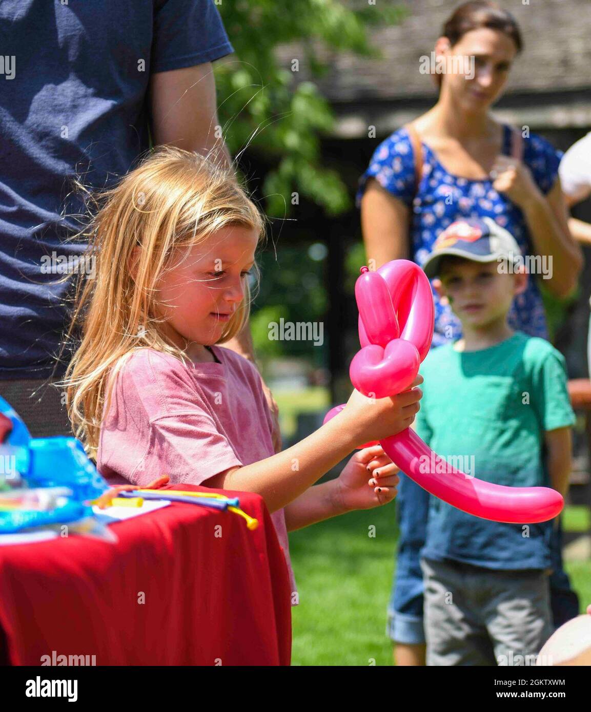 A child plays with a balloon animal during Bring Your Kid to Work Day ...