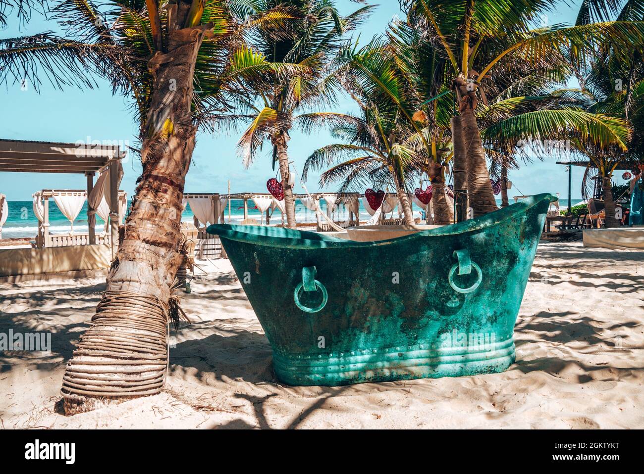 Retro style metal bath tub at beach resort with heart shape artwork hanging from tree Stock