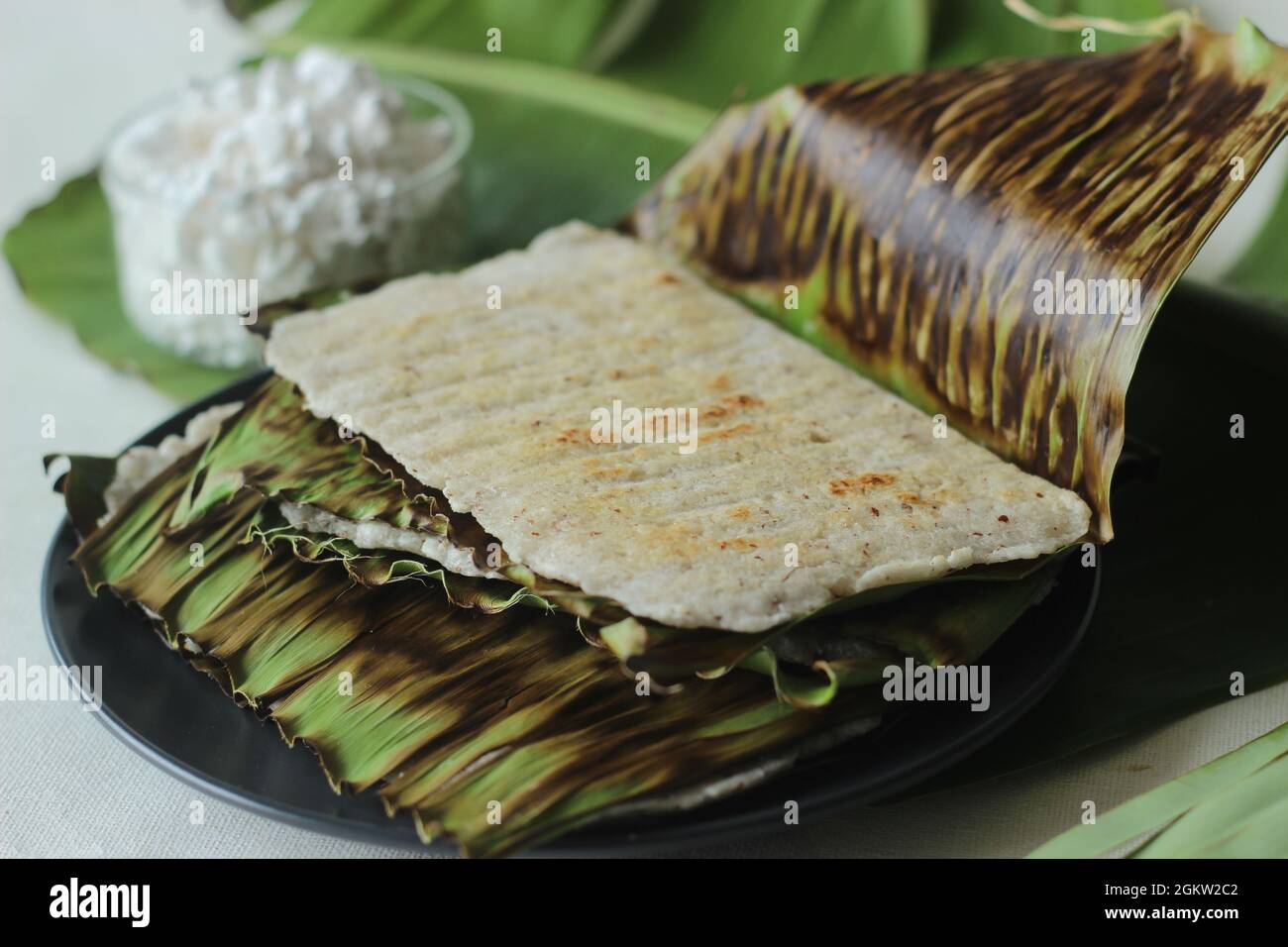 Arrowroot Ottada is a healthy wholesome snack. Made with ground arrowroot blended with coconut. Cooked on a tawa like appam wrapped with banana leaf. Stock Photo