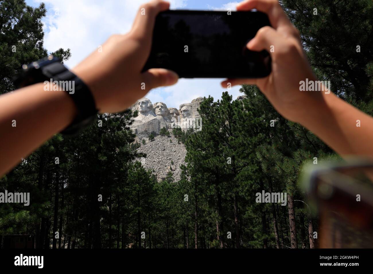 Hands holding phone taking picture of the sculpture of Mount Rushmore National Memorial. Keystone,South Dakota,USA Stock Photo
