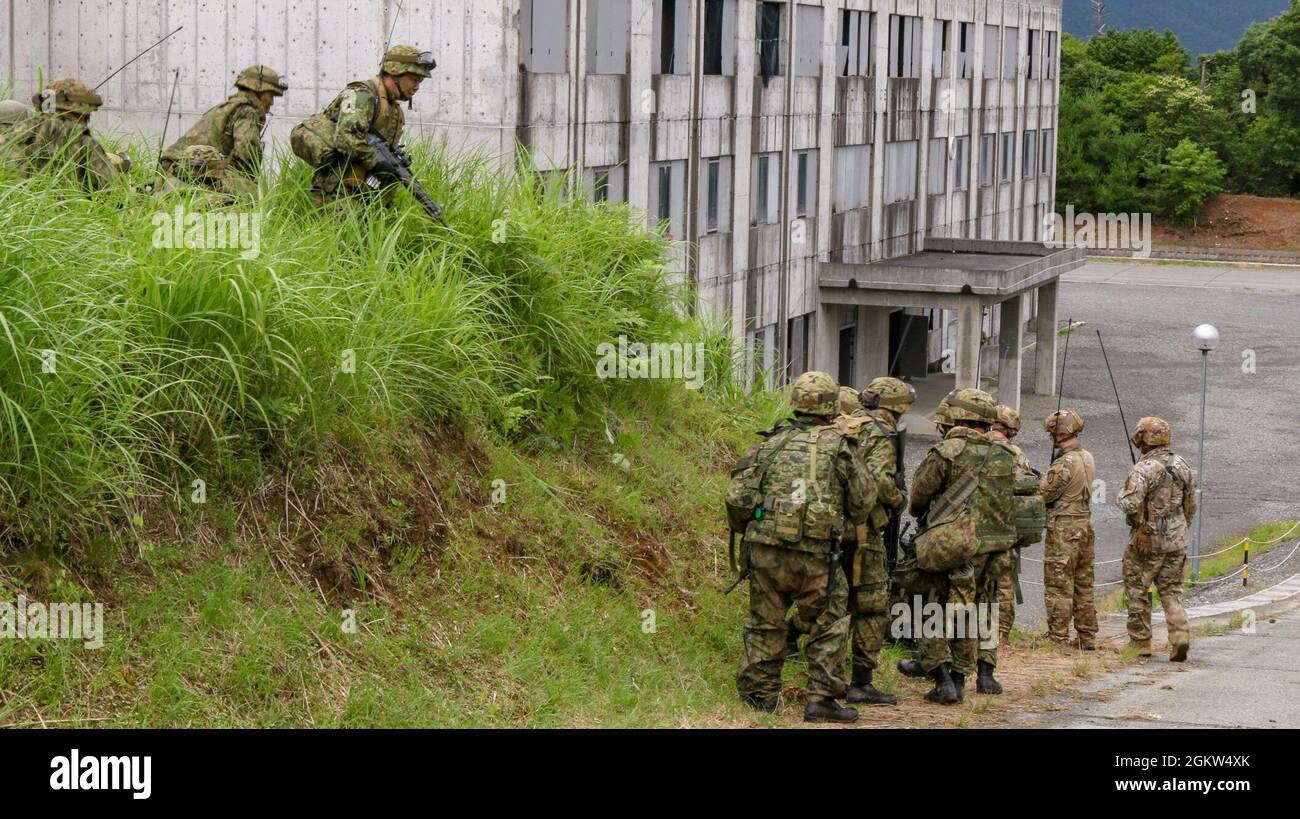 Members of Japan Ground Self-Defense Force wait for orders to clear a building on Aibano Training Area, Japan, July 1, 2021, as part of exercise Orient Shield. Orient Shield is the largest U.S. Army and JGSDF bilateral field training exercise being executed in various locations throughout Japan to enhance interoperability and test and refine multi-domain and cross-domain operations. Stock Photo