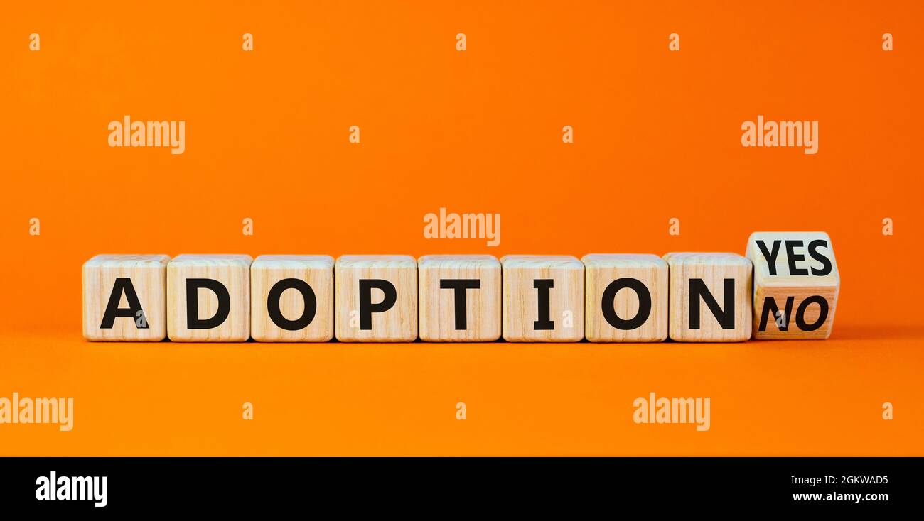 Adoption symbol. Turned a wooden cube and changed words 'adoption no' to 'adoption yes'. Beautiful orange background. Business and adoption concept, c Stock Photo