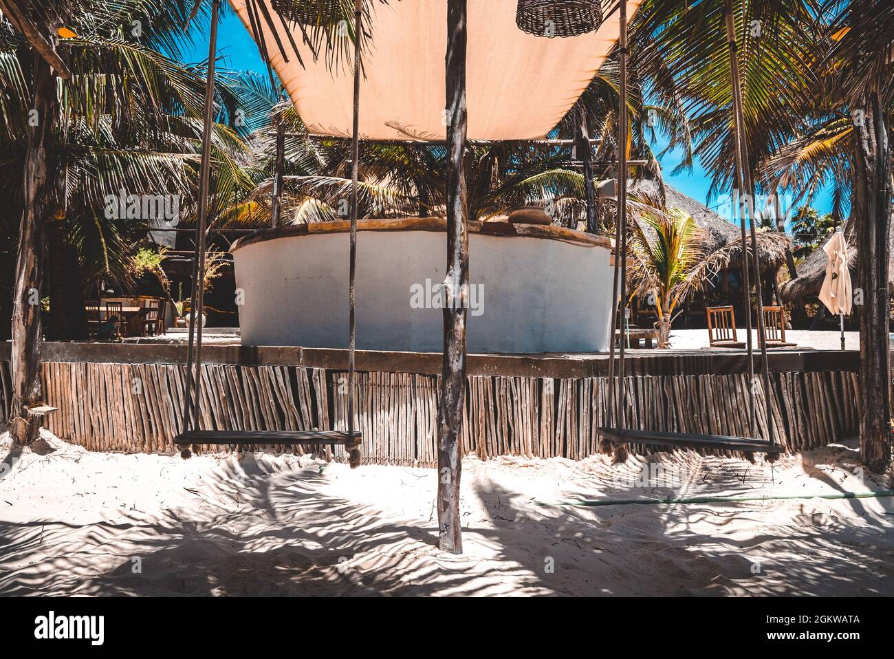 Hanging empty swing seats on sand at beach resort on a sunny day Stock Photo